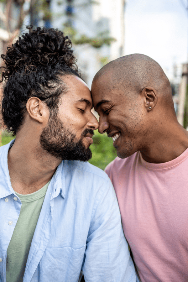 A happy gay male couple touching foreheads and smiling.